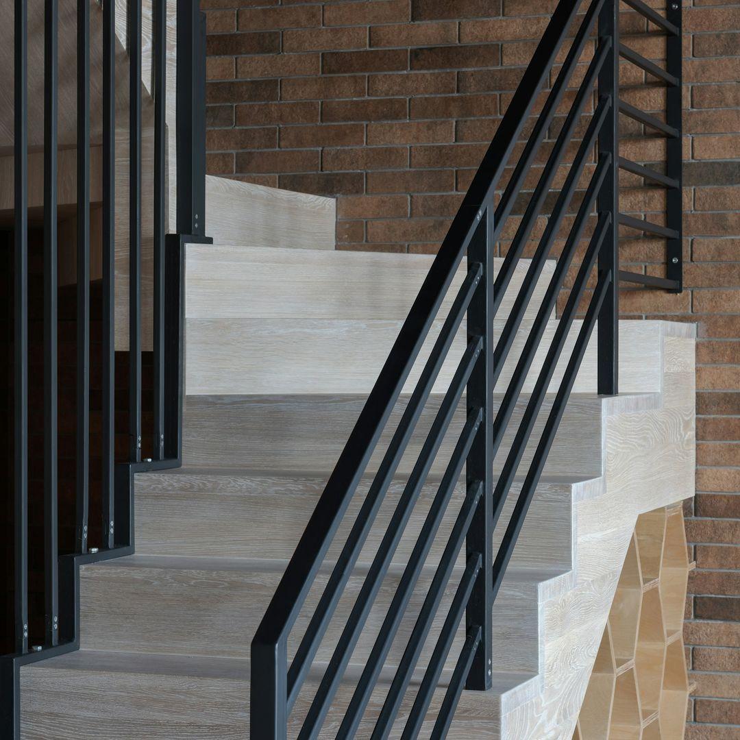 Graue Holztreppe mit schwarzem Handlauf